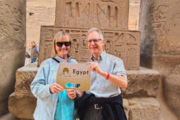 A picture of a couple in front of one of the statues in Luxor